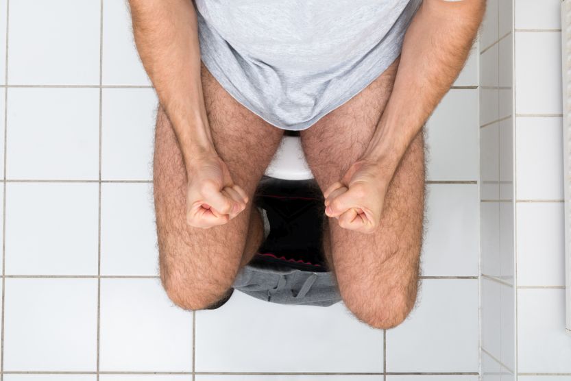Man Clenching His Fist Sitting On Toilet Bowl
