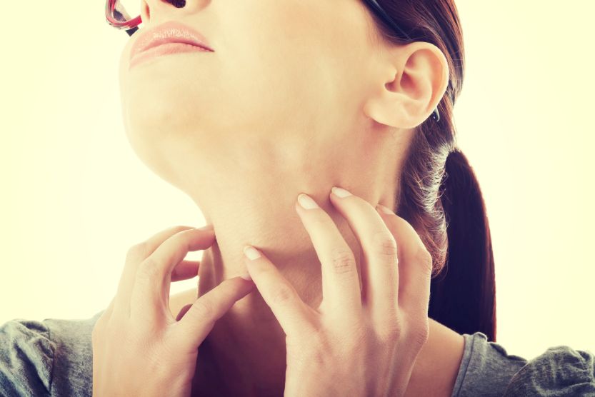 Young woman is scratching her neck.