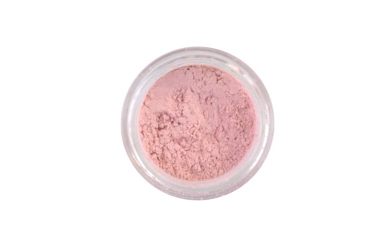 Loose pink with mother of pearl powder face makeup on white background